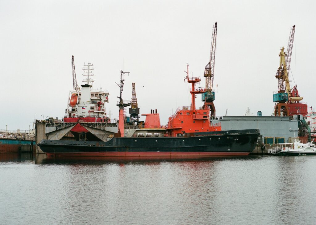 View of industrial cranes and ships docked at a port in Saint Petersburg, Russia. No people visible.